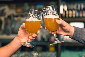 Close up of two hands holding beer glasses toasting