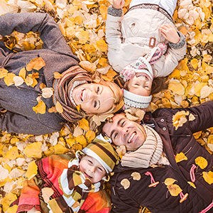 family laying on yellow fall leaves smiling
