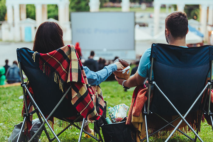 couple sitting in camping chairs watching outdoor movie