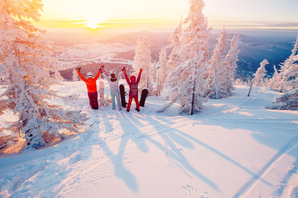 Group of snowboarders on snowy mountain with the sunset in the background
