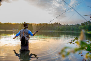 Young man fly fishing at sunrise